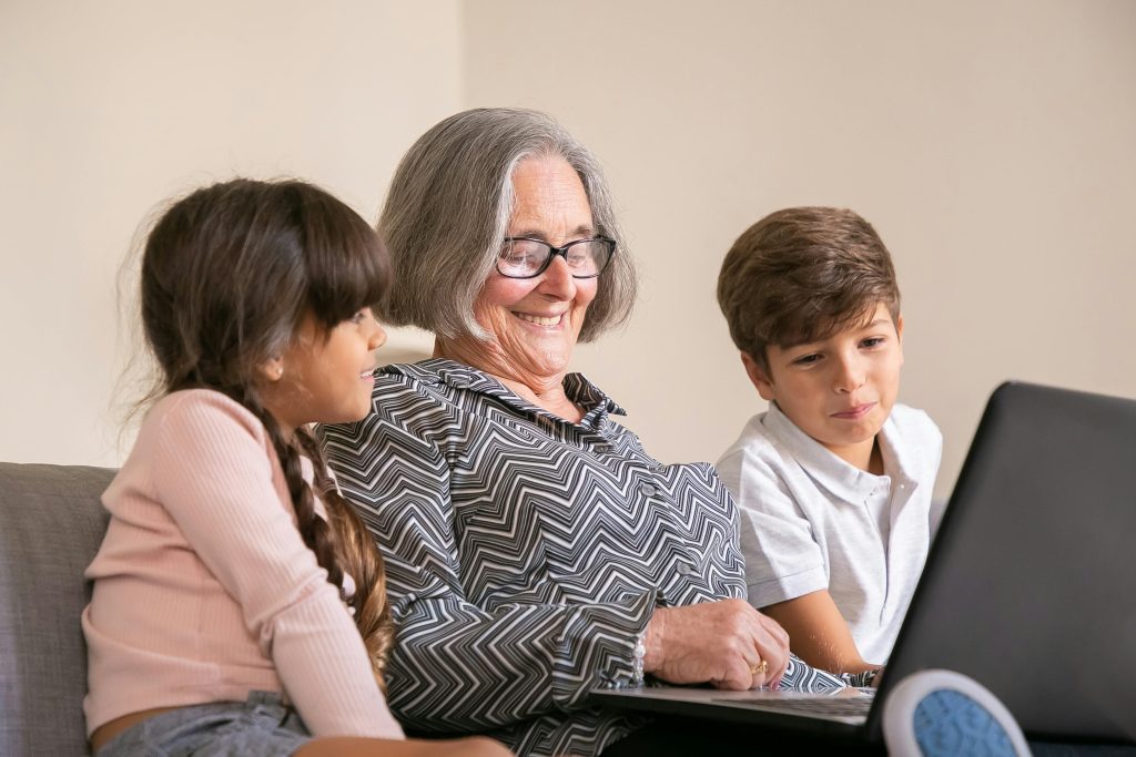 A grandmother sharing time with grandchildren at laptop